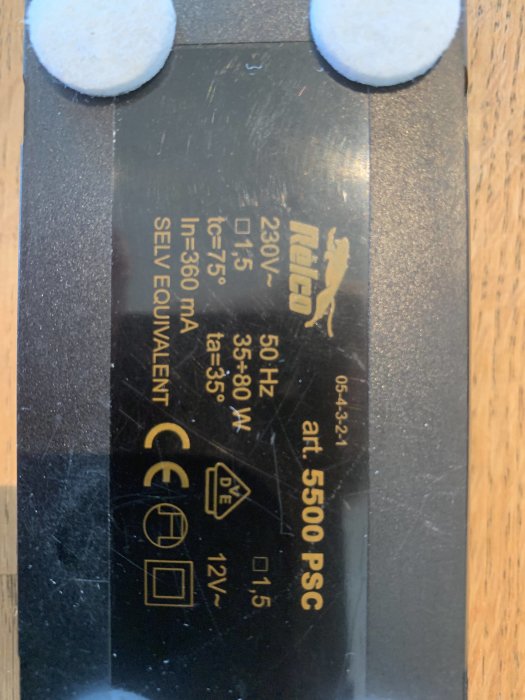 Etikett på en trasig touchdimmer med tekniska specifikationer, 230V och CE-märkning.