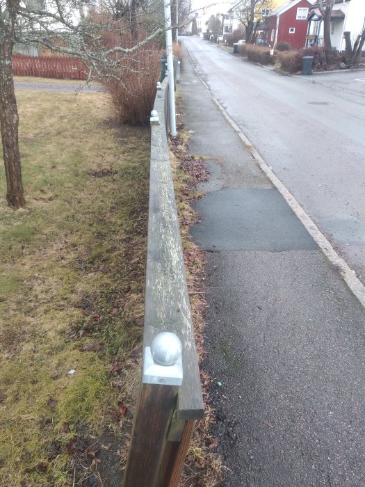 Staket längs med en gata med stolpar och stolpskor löst satta, synlig skada och ruckbarhet.
