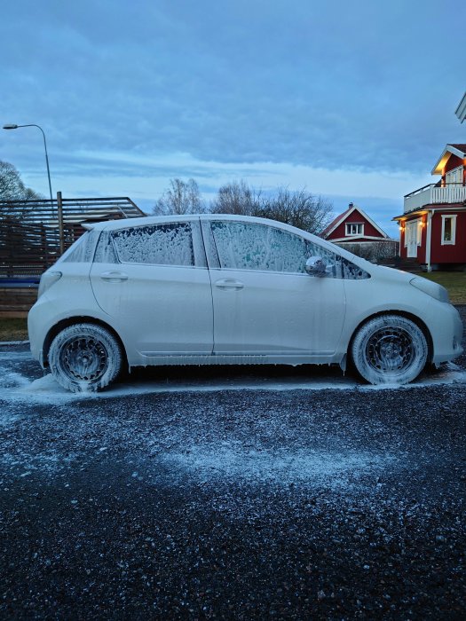 Bil täckt av tjockt lager is efter en kall natt parkerad utomhus.