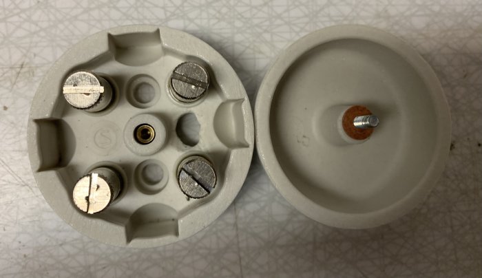 Två delar av en 50 mm modell av en elektrisk dosa, den ena öppnad för att visa interna skruvar.