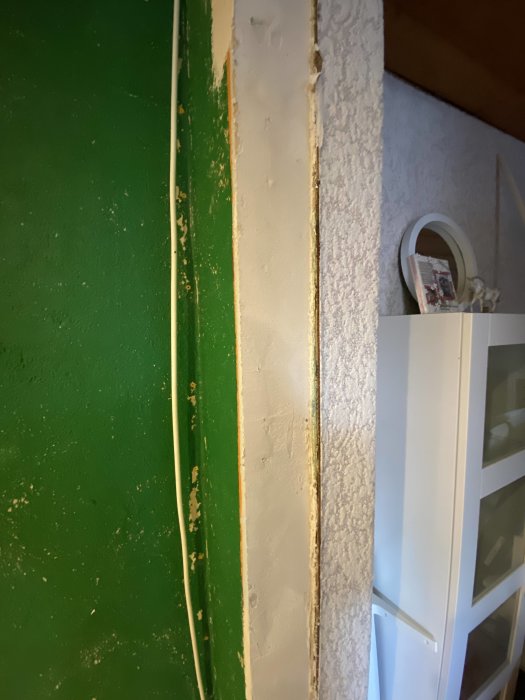 Vägg med utjämnat spackel vid dörrkarm för att förbereda montering av ny karm.