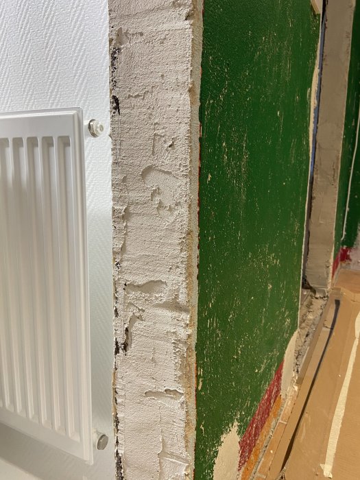 En spacklad vägg med ojämnheter vid en radiator, förberedd för dörrkarmsmontering.