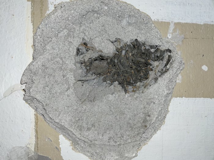 Defekt i puts med synlig träull på en vägg under renovering.