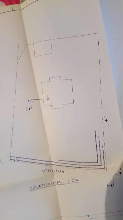 Situationsplan ritning som visar en fastighets layout med stödmur markerad.