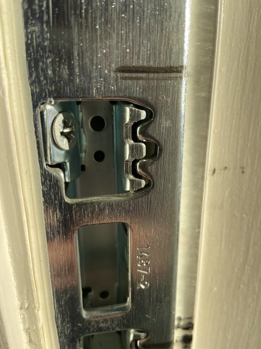 Närbild på ett installerat slutbleck i en dörrkarm potentiellt i behov av justering.