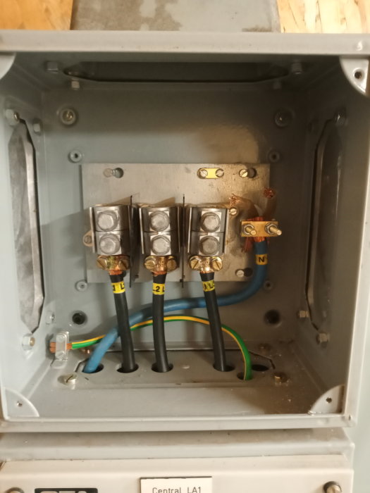 Inmatningslåda för el med anslutna kablar och tydligt markerade säkringsgrupper i ett metallskåp.