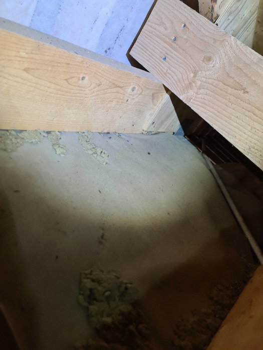 Bild på en trästolpe och vinkeljärn i en entretrappa, stolpen visar tecken på röta.
