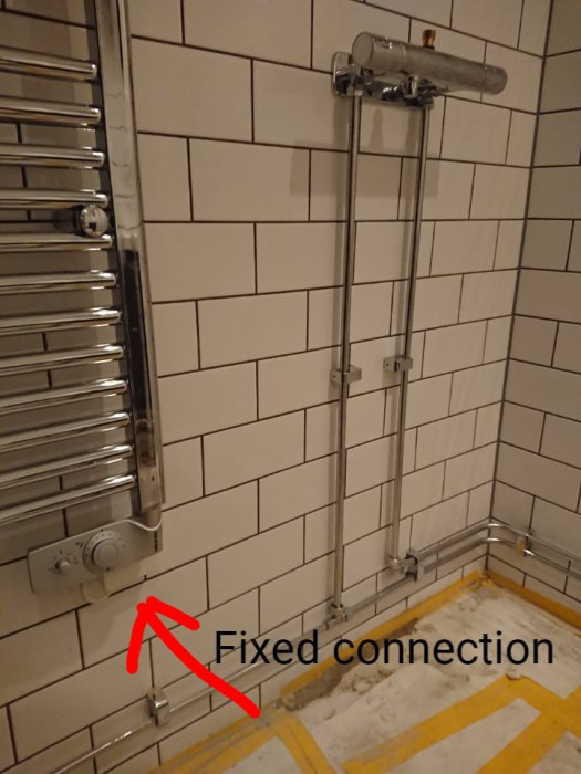 Towel dryer in bathroom connected to fixed electrical connection on tiled wall.