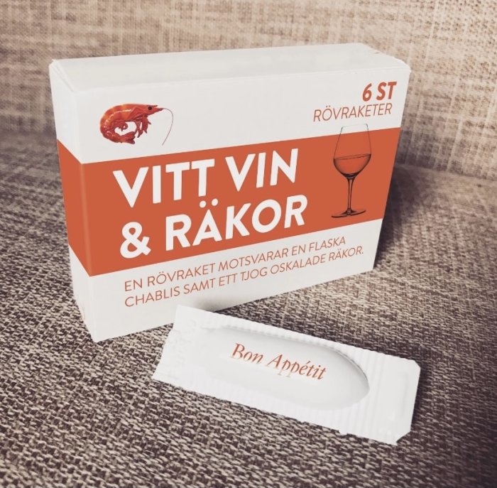 Förpackning märkt "VITT VIN & RÄKOR" med beskrivning och individuellt inslaget godis framför.