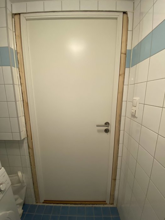 Nyinstallerad badrumsdörr med synliga avstånd mellan kakelvägg och karm.
