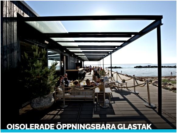 Utomhusrestaurang med gäster under öppningsbara isolerade glastak med havsutsikt.