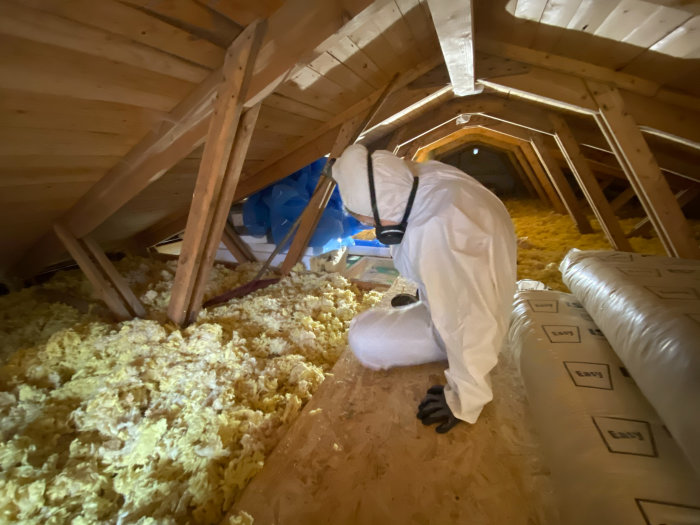 Person i skyddsdräkt isolerar vind med lösull.