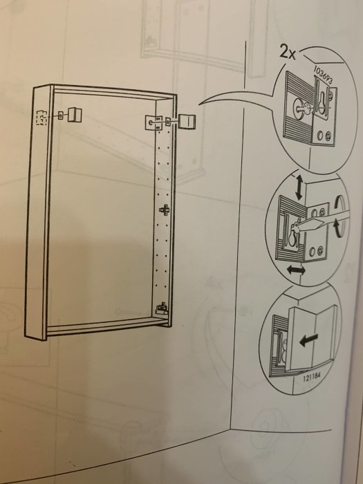 Monteringsanvisning för ett väggskåp som visar skåpet fäst vid väggen med två beslag.