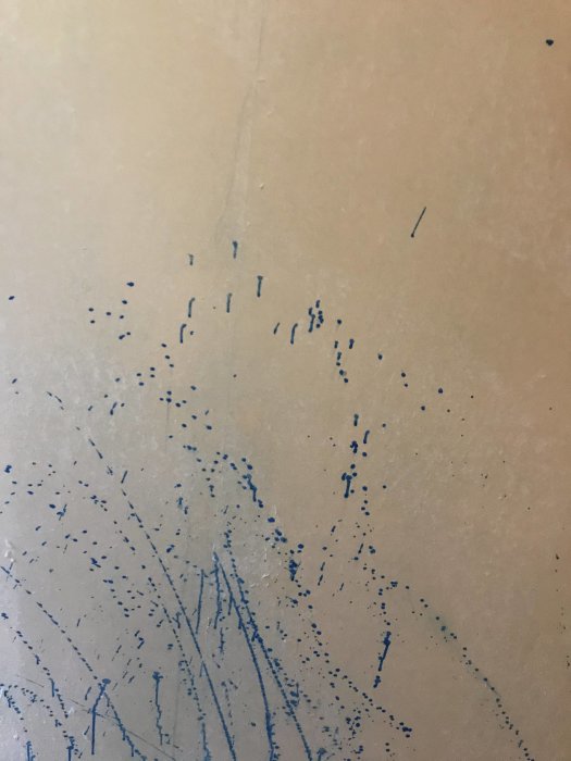 En vägg med blå färgstänk och spår av bredspackling.