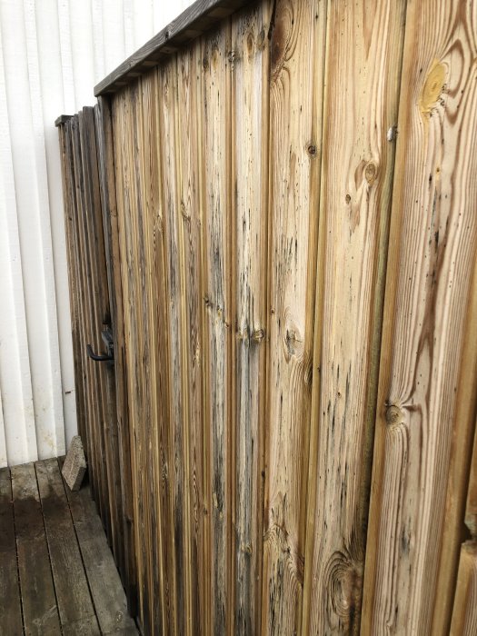 Altanens tryckimpregnerade trästaket som visar tecken på missfärgning och slitage.