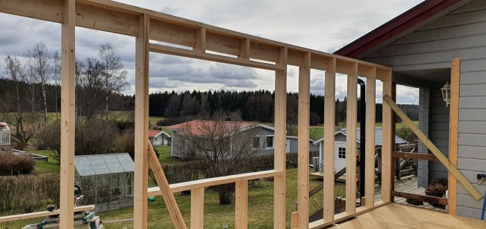 Halvfärdigt trästomme av en vägg på ett byggprojekt med landskap i bakgrunden.