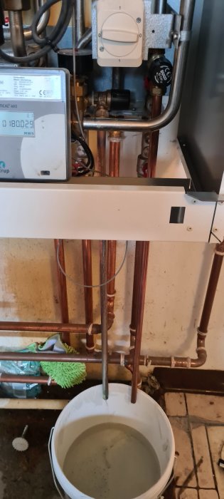 Värmesystem Danfoss ECL110 med öppen ventil och hink för att tömma vatten.