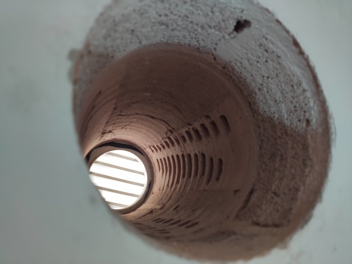 Vy inifrån ett tomrum av ett ventilationhål i en vägg, visar lagren av material.