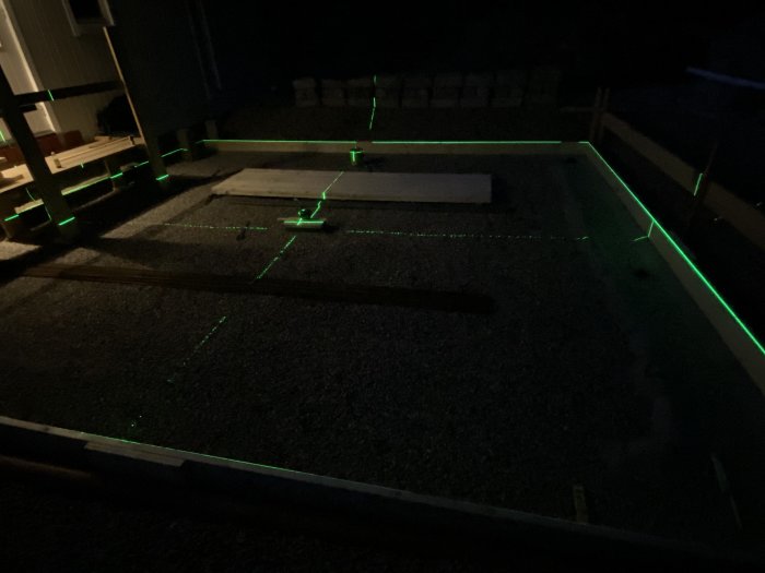 Utgrävd krypgrund för utbyggnad markerad med grön laser för exakthet på natten.