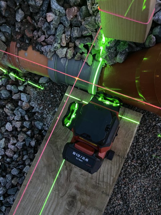 Laserpass används för att mäta raka linjer på träreglar i en utgrävning för husbygge.