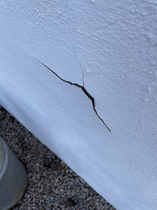 En närbild av en sprucken och flagande vit husgrund med synlig skada och färg som lossnat.