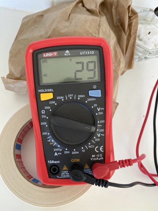 Multimeter som visar 29V på skärmen, vilket indikerar restspänning efter att ha slagit från en säkring.