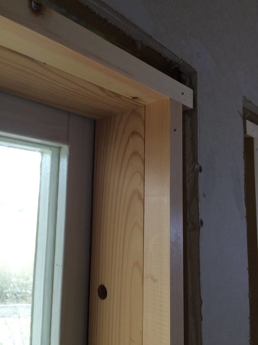 Hyvlad furubräd som används som fönstersmyg vid ett fönster, med märken efter försiktigt sågande för att undvika flisor.