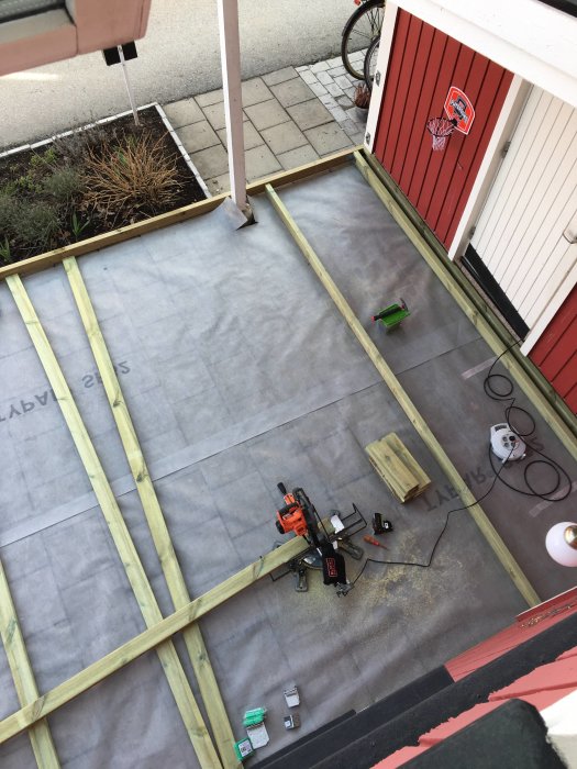 Översiktsbild på ett pågående byggprojekt med träreglar och verktyg utspridda på en presenning.
