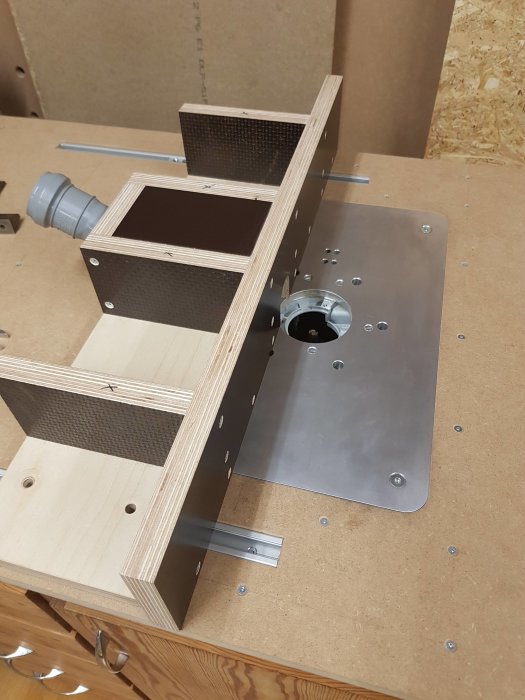 Prototyp av hemmagjort fräsbord med monterad aluminiumplatta och anslutning för dammsugning.