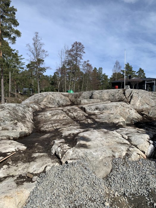 Bild av ett rengjort berg i en trädgård med grus och planer för en framtida altan.