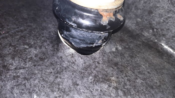 Genomträngning under tvättstället med möjliga mögelspår på svart rör och tätningsmaterial.