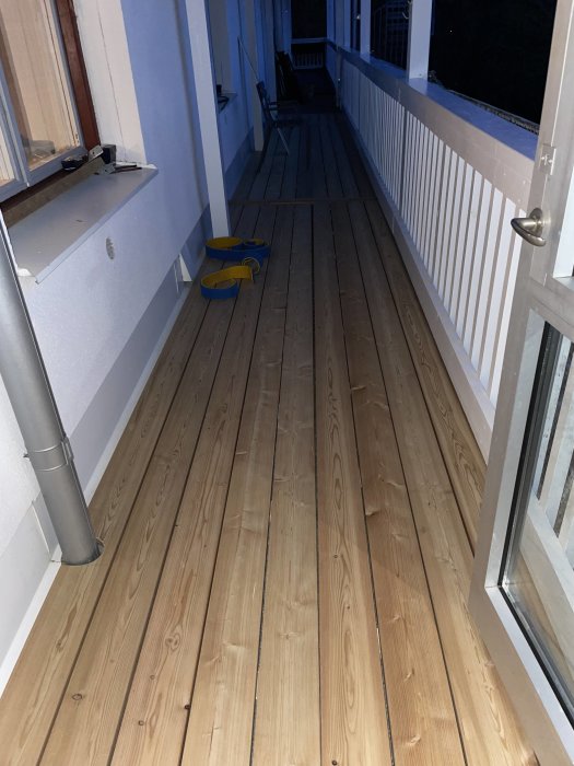 Trätrall på balkong med aluminiumdurk och synliga gula skor vid sidan.