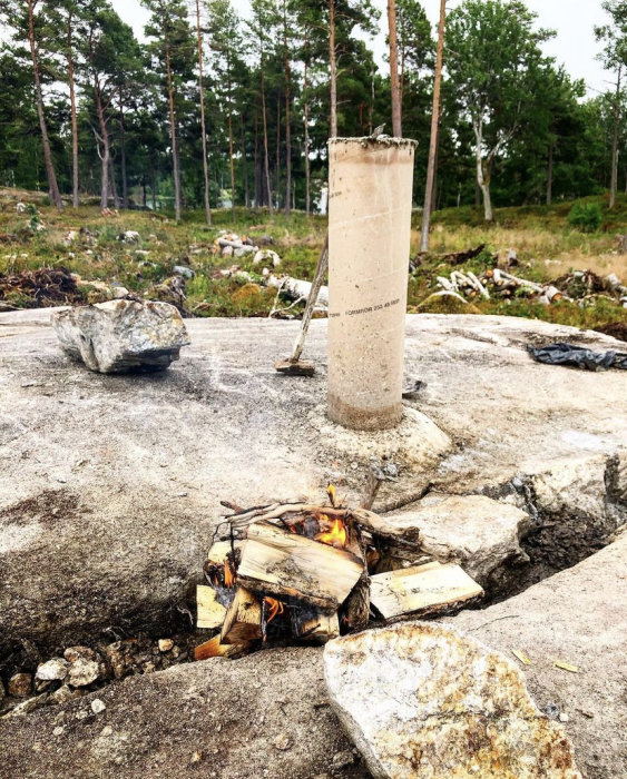 Eldningsteknik för att skapa dräneringskanal i hårt bergslandskap, med brinnande ved och rörkonstruktion.