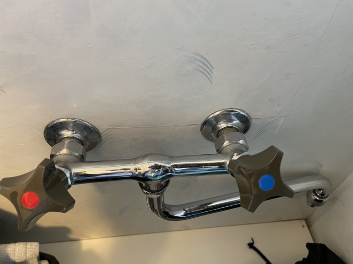 Vattenutkastare med röd och blå markör för varmt och kallt vatten monterad på vägg.