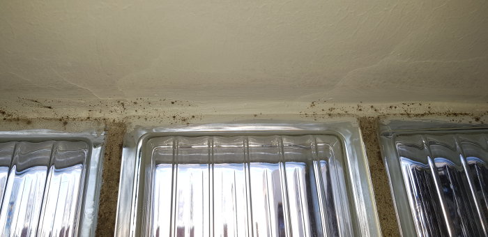 Svarta prickar som misstänks vara mögel runt kant på högt sittande fönster i källarlägenhet.