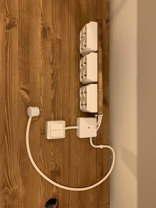 Fyra vita vägguttag monterade på träplanka med en inkopplad strömbrytare och kabel.