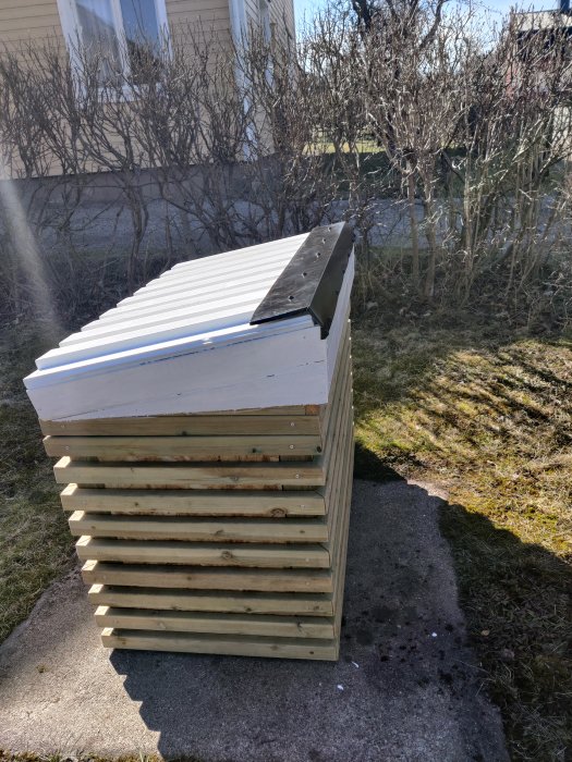 Hemmagjord sandlåda av tryckimpregnerat och spillvirke med säkert lock står i en trädgård.