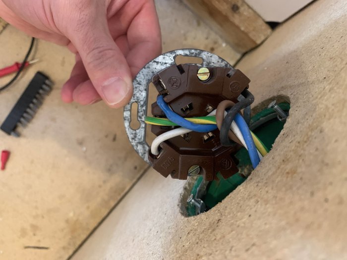Elektrisk uttagsinstallation med synliga kopplade ledningar inklusive 230V, N och PE i en vägg.