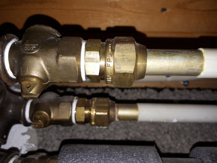 Mässingskoppling ansluten till ett 15mm prisolrör inom VVS-installation.