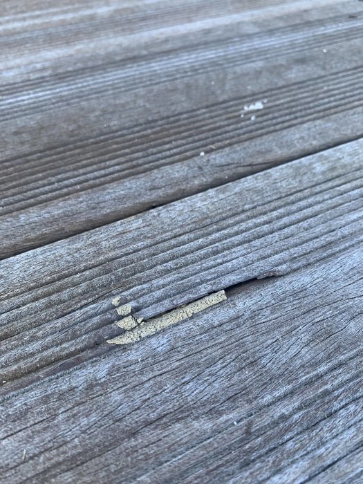 Okänd avlagring på trätrall nära en springa.