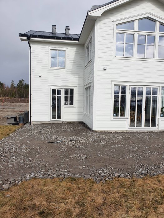 Vit villa med markerad yta för betongaltan nära husets kantelement och gräsmatta.