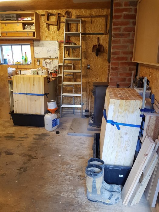 Verkstadsinteriör med staplar av avkapade träspjälor, sågspån och verktyg, process för staketbygge.