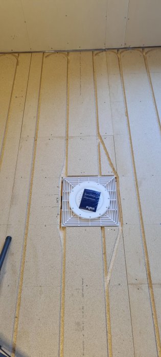 Nylagd golvbrunn med anslutande avloppsrör på en betongplatta under konstruktion.