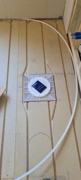 Nylagt värmegolv med synliga slingor och central golvvärmeuttaget i en byggkonstruktion.