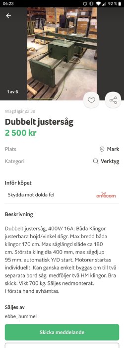 Grön dubbel justersåg i en verkstadslokal med pallar och förpackningar i bakgrunden.