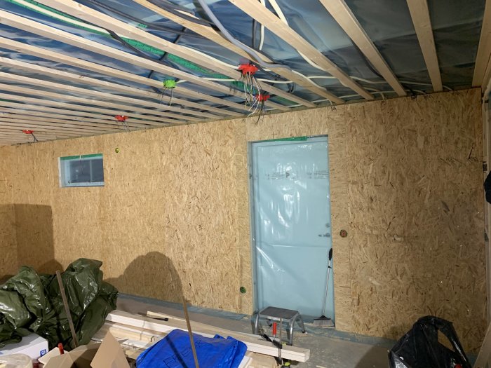Renoveringsförfarande med isolering och OSB-skivor på en vägg i ett pågående byggprojekt.