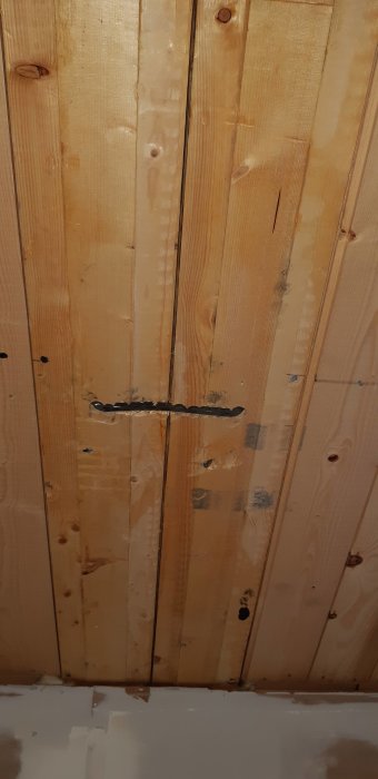 Träbjälklag sett inifrån genom öppning, med bjälkar som går parallellt och en eventuell balk.