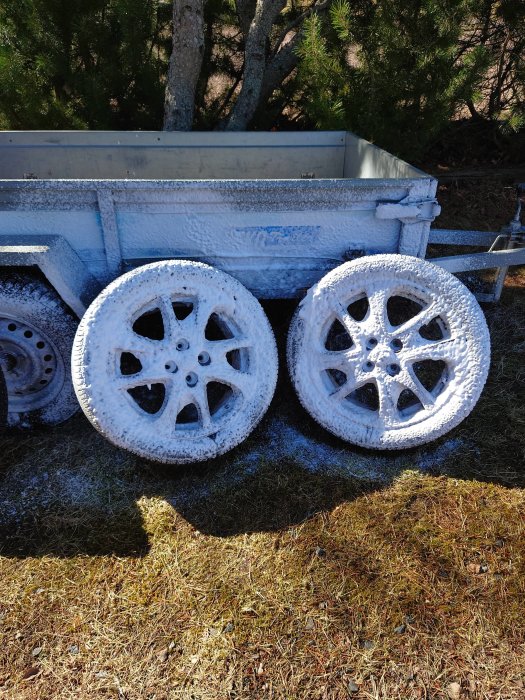 Bilhjul och släpvagn täckta med skumtvättmedel under bilvård.