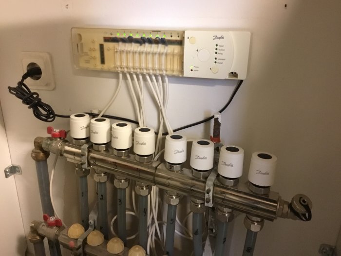 Värmesystem med rör och Danfoss Masterregulator på väggen med lysdioder och justerbara ventilationsreglage.