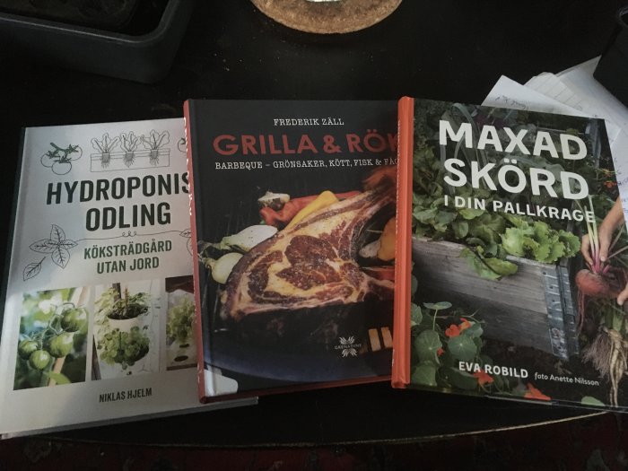 Tre kokböcker om hydroponisk odling, grillning och odling i pallkragar på ett bord.